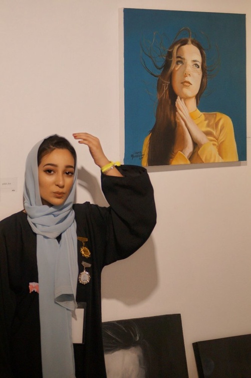 منار غزاوي مع احدى لوحاتها الفنية