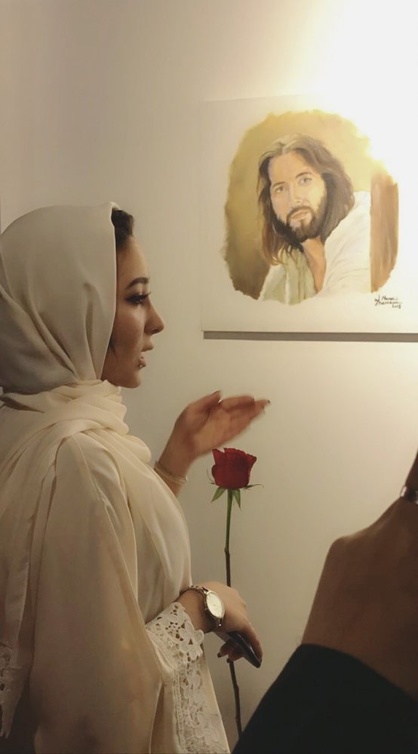 الفنانة منار غزاوي بجانب احدى لوحاتها